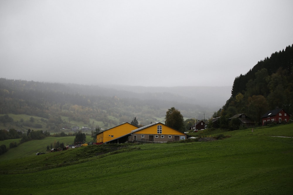 a yellow house sitting on top of a lush green hillside