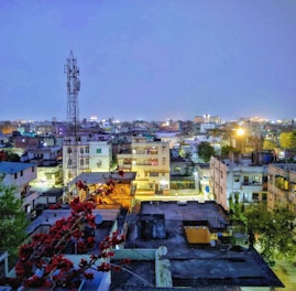 A vibrant cityscape at dusk showcasing a mix of residential and commercial buildings illuminated warmly.