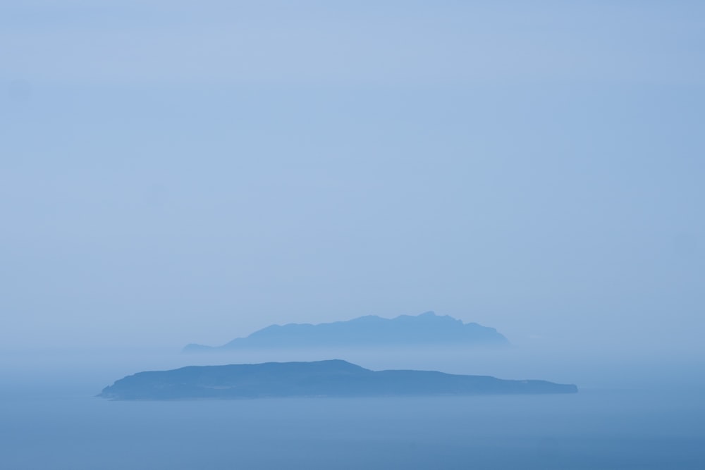 an island in the middle of the ocean on a foggy day