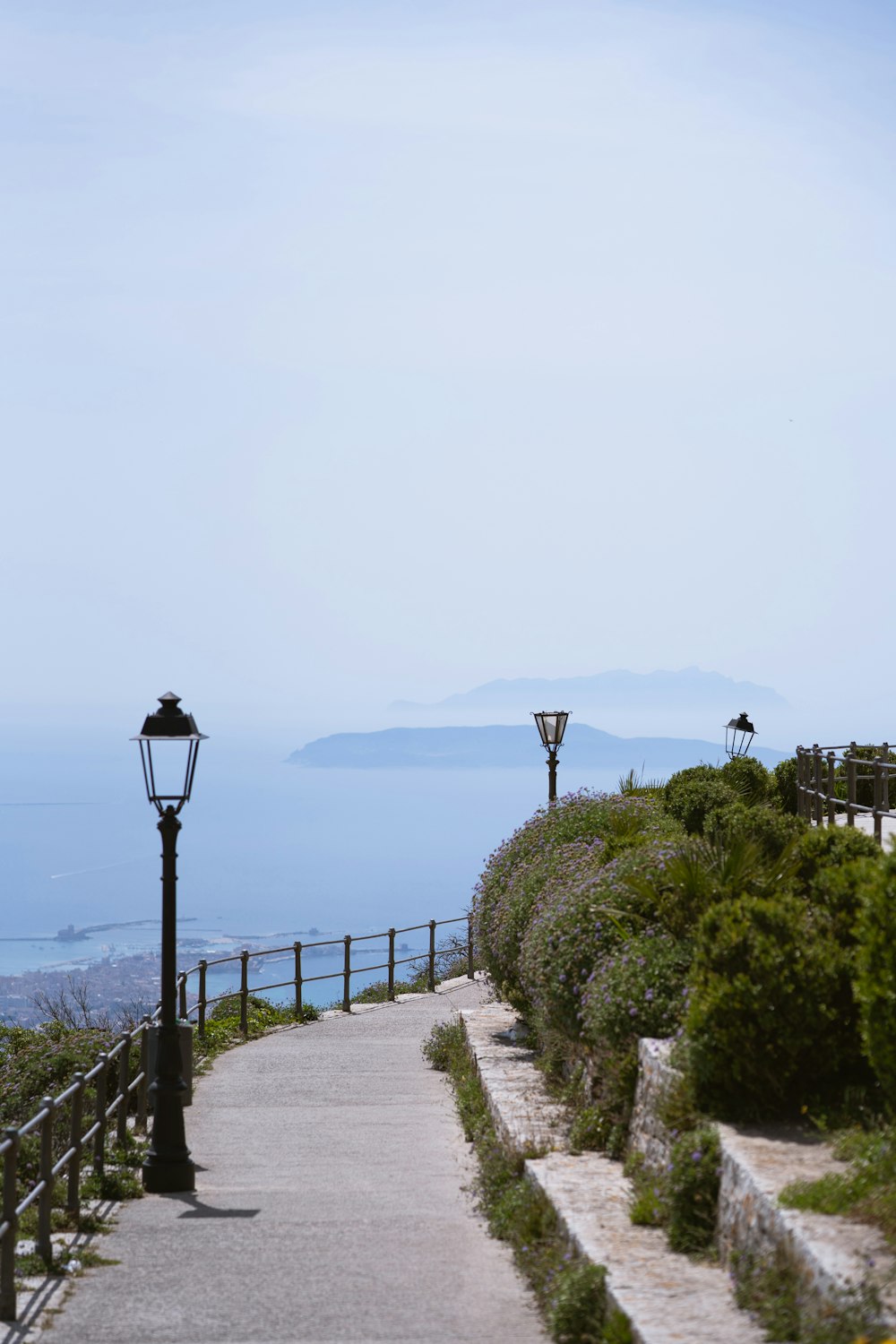 a walkway leading to the ocean with a lamp post in the foreground