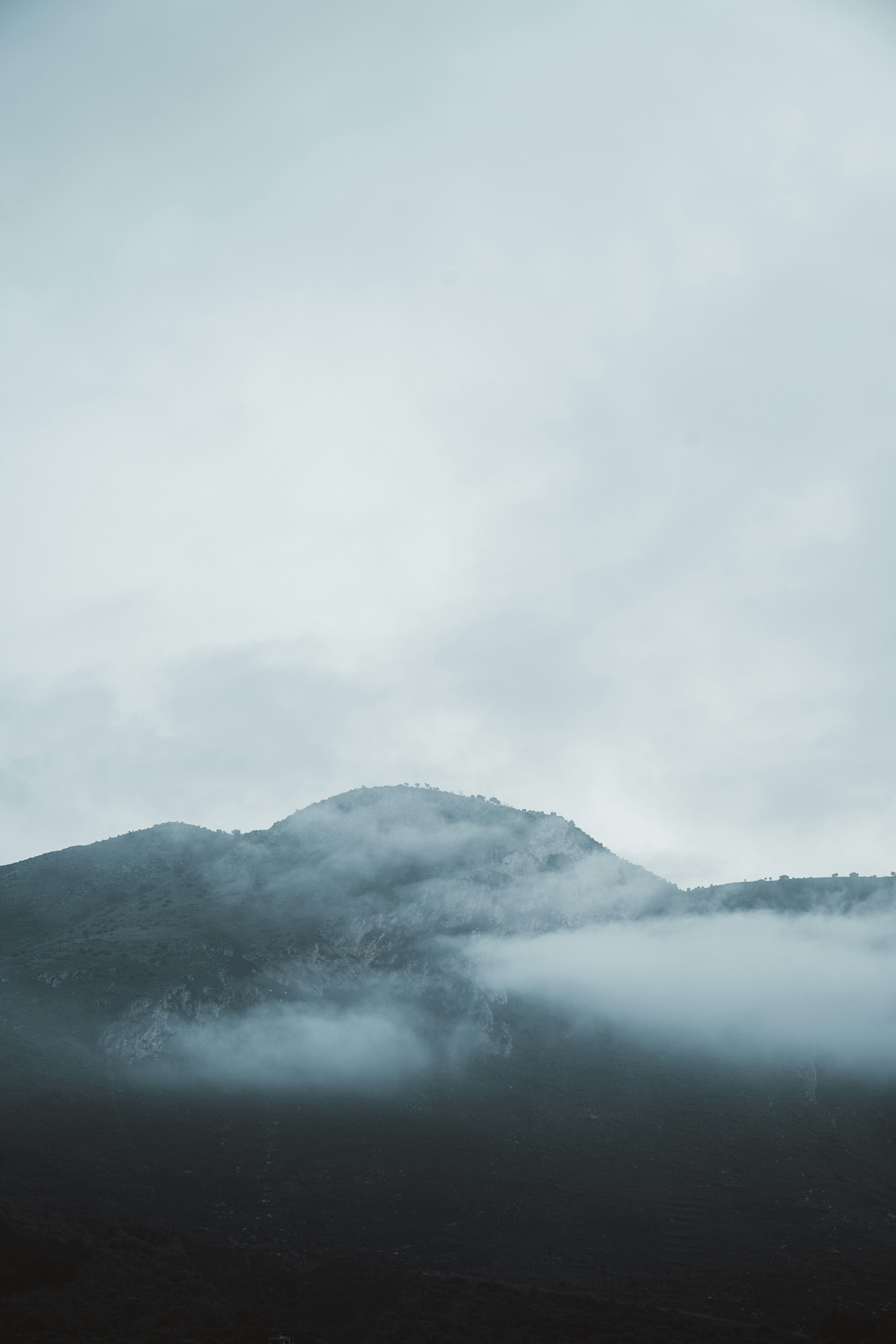 a mountain covered in fog and clouds on a cloudy day