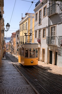 a yellow trolley car traveling down a street next to tall buildings