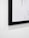 A close-up of a framed black and white photo hanging on a minimalist gallery wall.