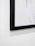 Close-up of a vibrant digital art print framed in a sleek black and gold frame hanging on a white wall.