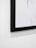 A close-up of a framed black and white photo hanging on a minimalist gallery wall.