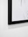 Close-up of a finely crafted frame around a graphic print hanging in a bright hallway.