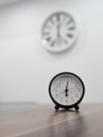 a black clock sitting on top of a wooden table