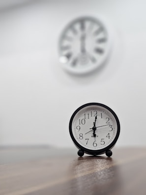 a black clock sitting on top of a wooden table