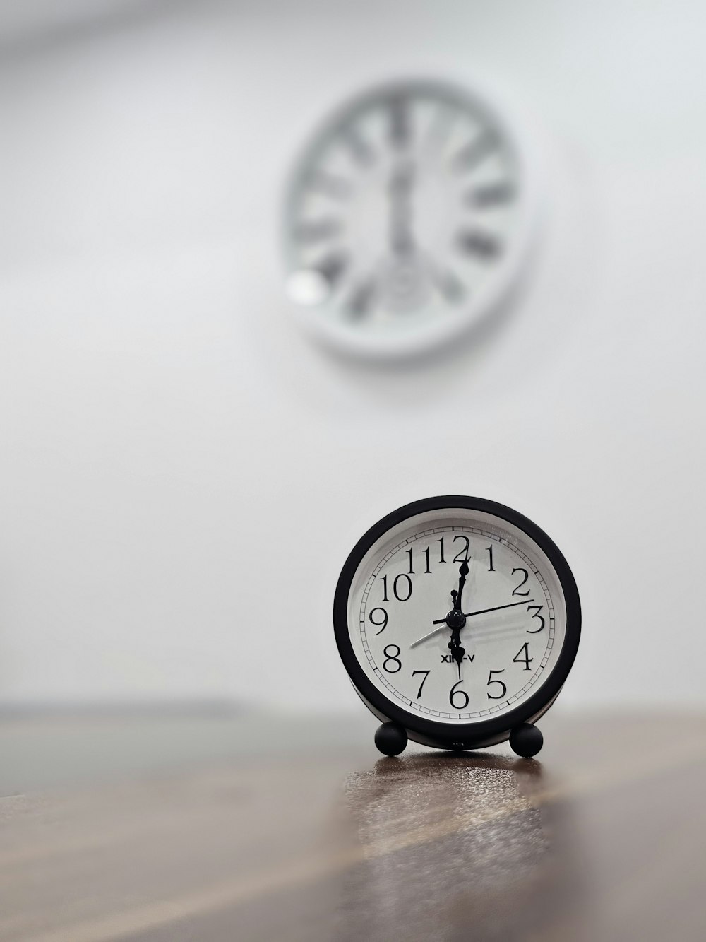 a black clock sitting on top of a wooden table