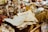 A variety of antique and vintage items are spread across a table. These include old newspapers, brass and glass bottles, ornate figurines, a wire basket filled with spherical objects, and large crystals or minerals. The scene conveys a sense of history and nostalgia.