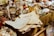 A variety of antique and vintage items are spread across a table. These include old newspapers, brass and glass bottles, ornate figurines, a wire basket filled with spherical objects, and large crystals or minerals. The scene conveys a sense of history and nostalgia.