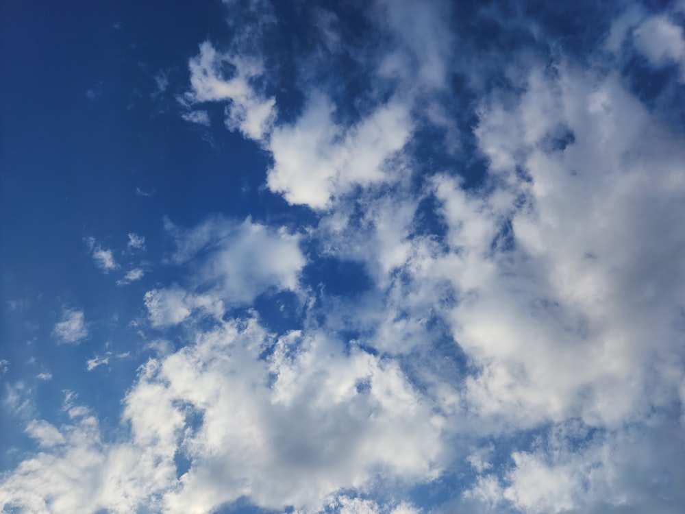 a plane flying through a cloudy blue sky