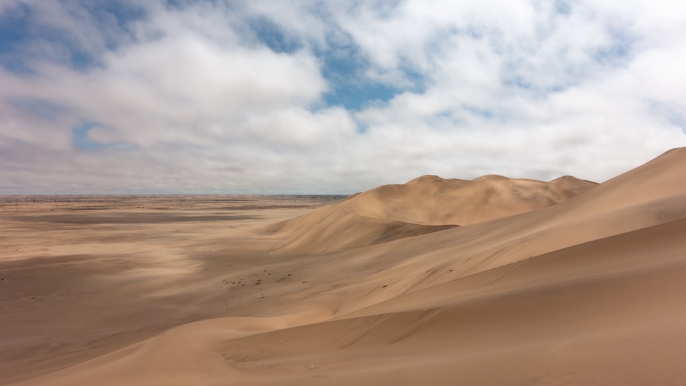 Eine Wüstenlandschaft mit Sanddünen und Wolken