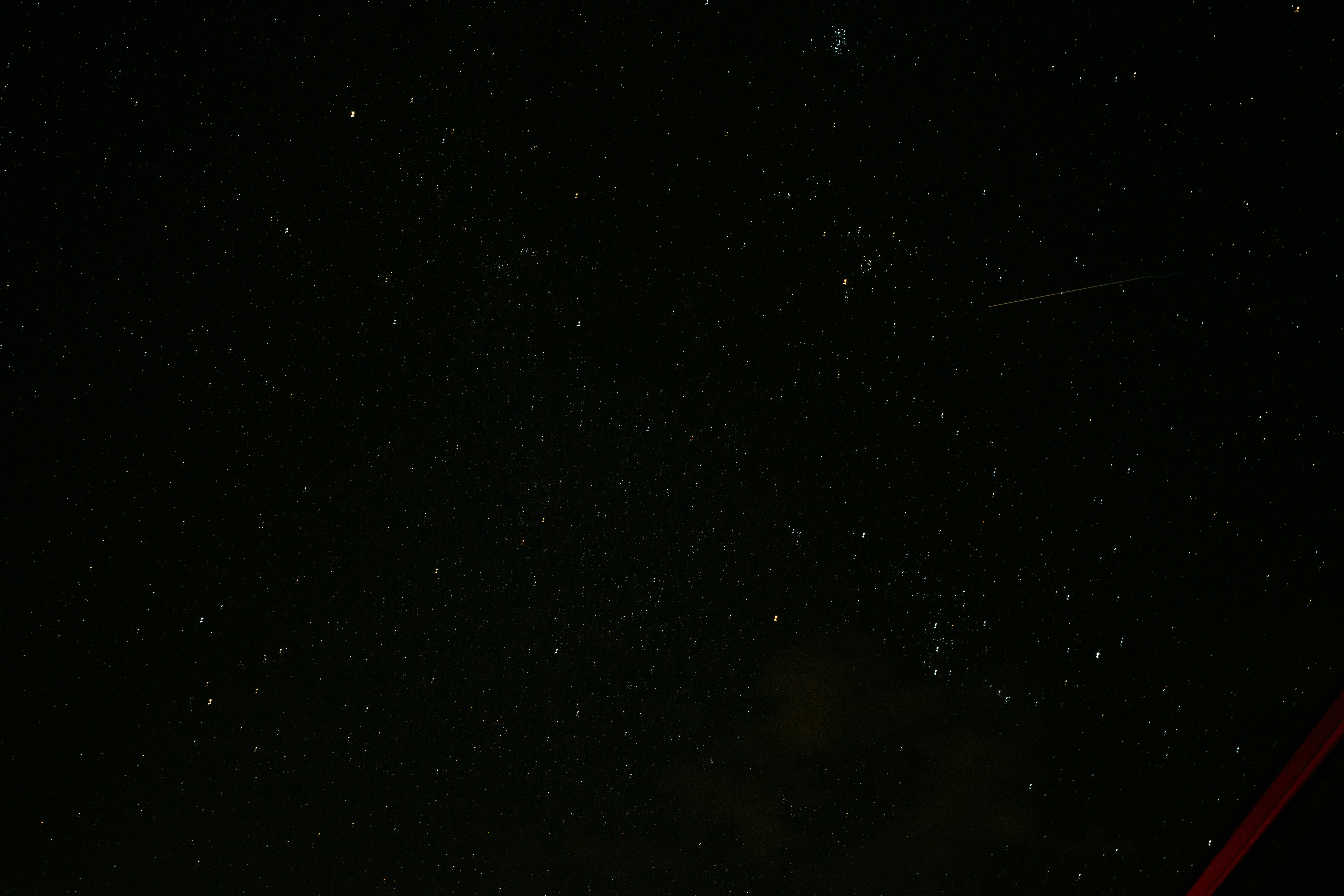 a night sky with stars and a plane in the distance