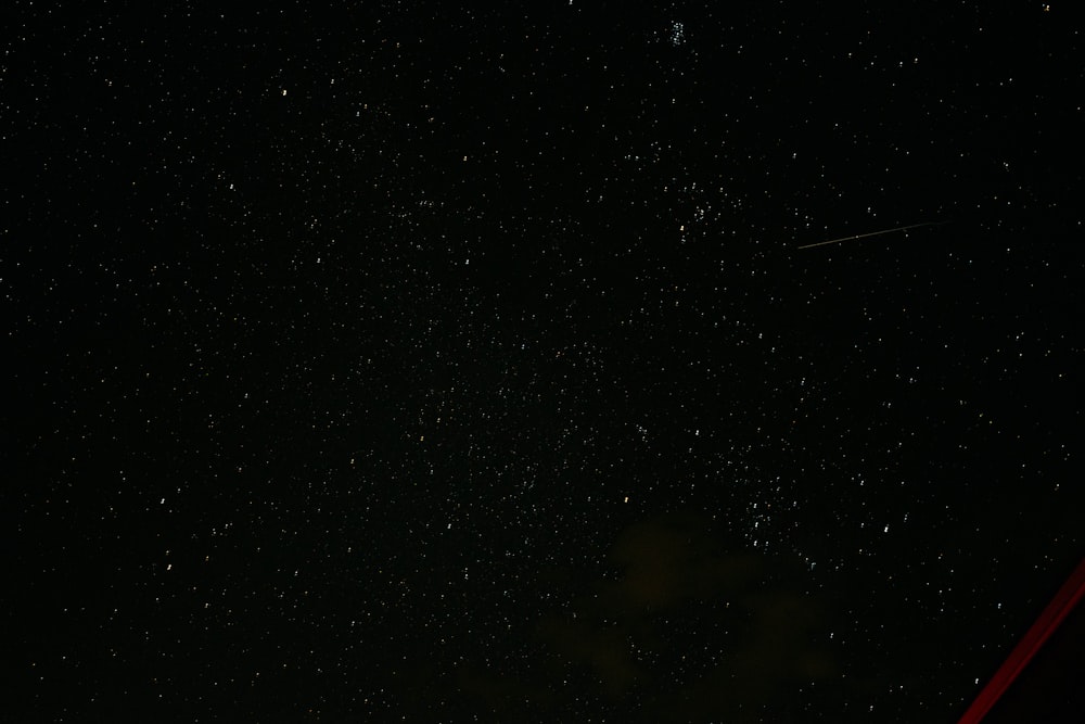 a night sky with stars and a plane in the distance