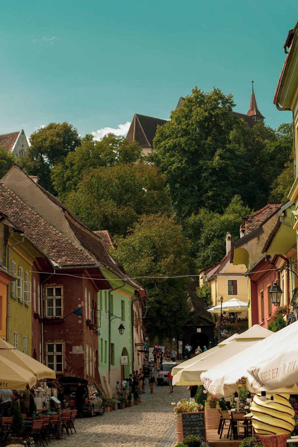 a cobblestone street lined with tables and umbrellas