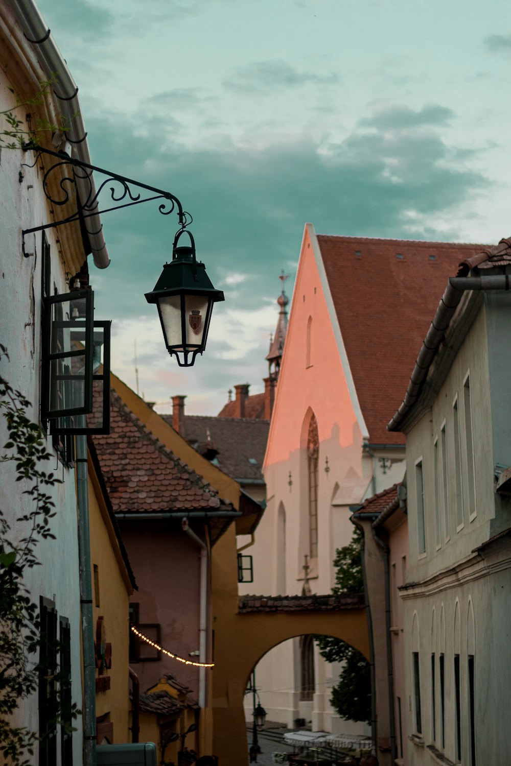 a narrow street with a light hanging from the side of it