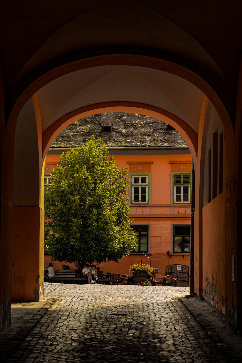an archway leading to a building with a tree in the middle