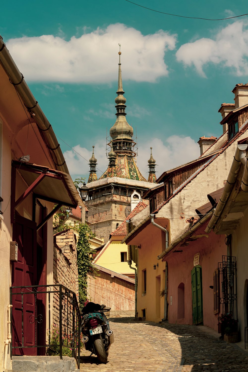 a cobblestone street lined with buildings and a steeple