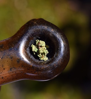A vibrant close-up of a handcrafted glass pipe resting on a rustic wooden table, surrounded by colorful cannabis leaves and small trinkets.