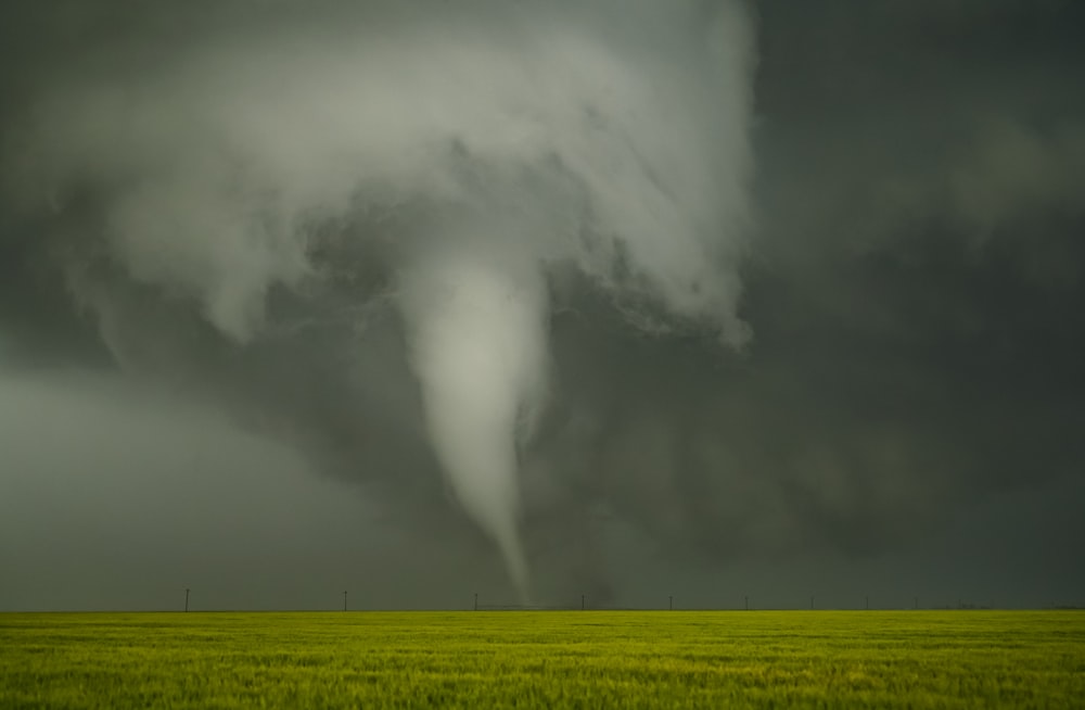 a large storm cloud looms over a green field