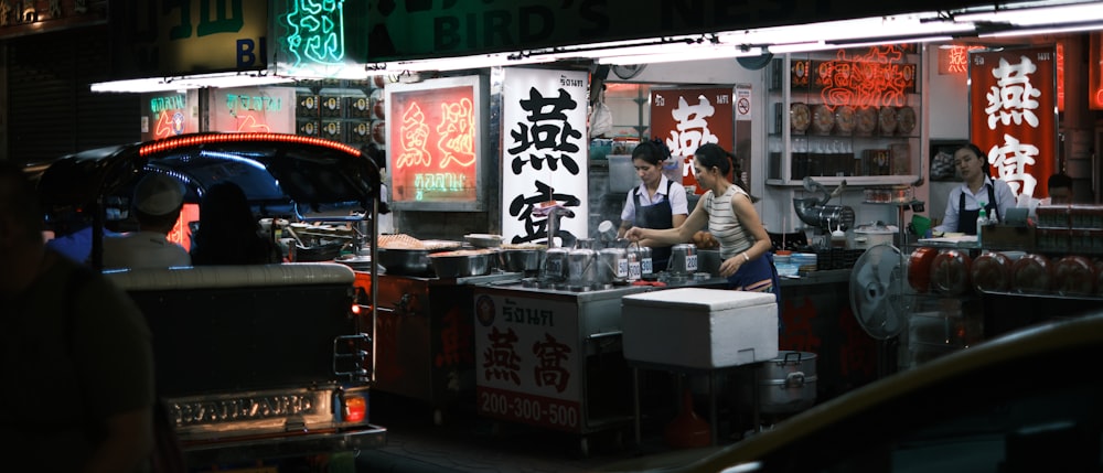 a woman standing in front of a food stand at night
