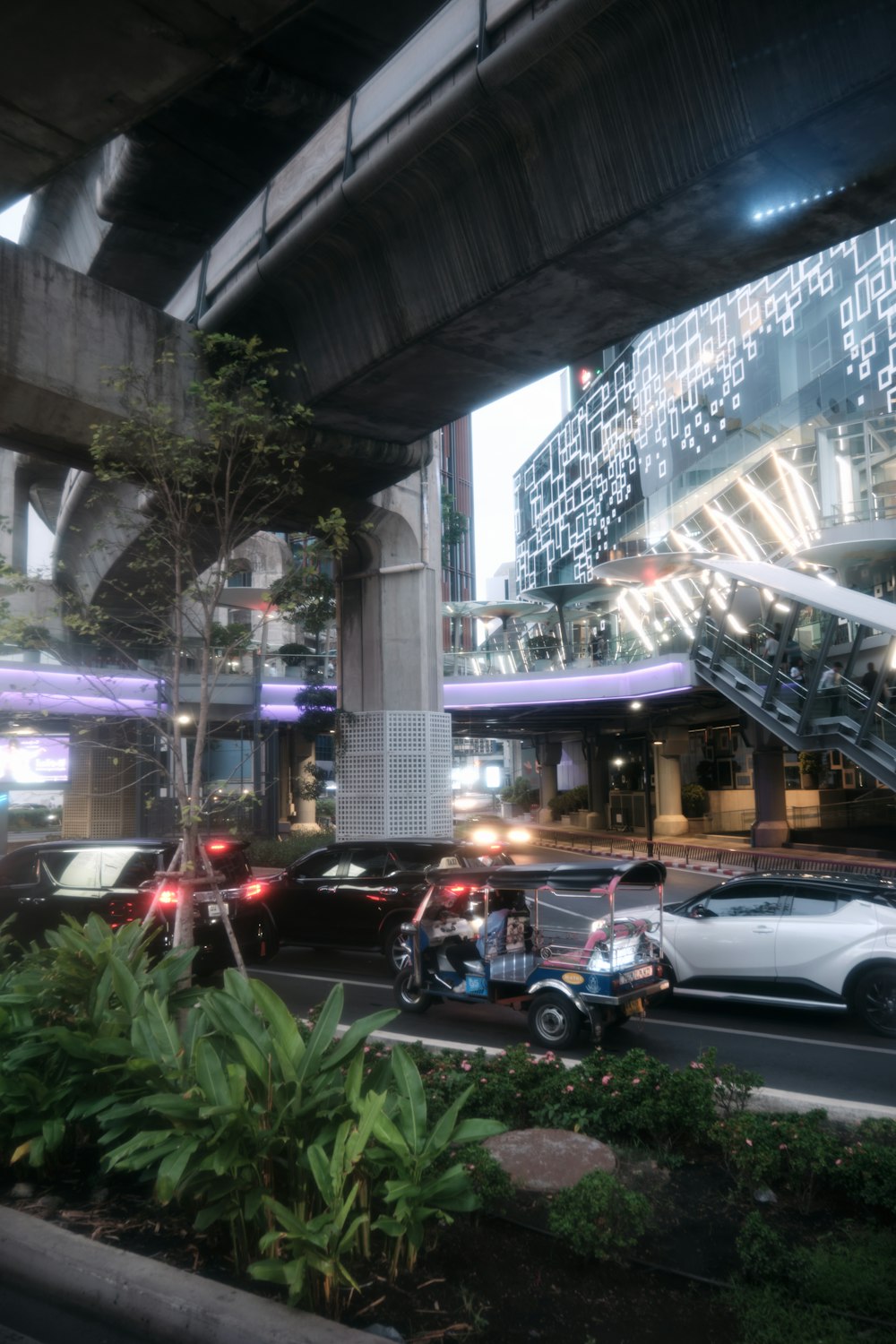 a city street filled with lots of traffic under a bridge