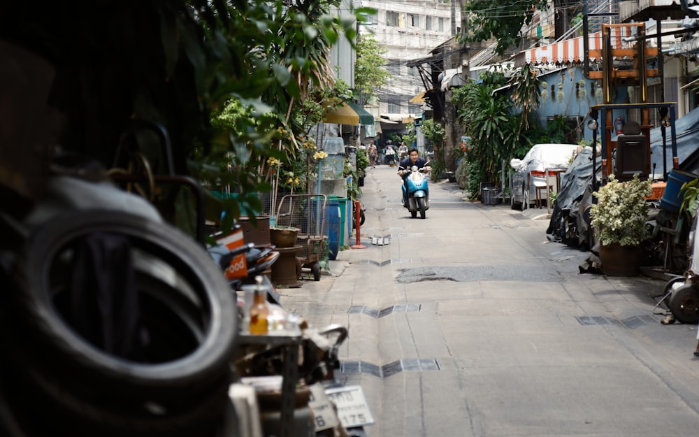 a man riding a motorcycle down a narrow street