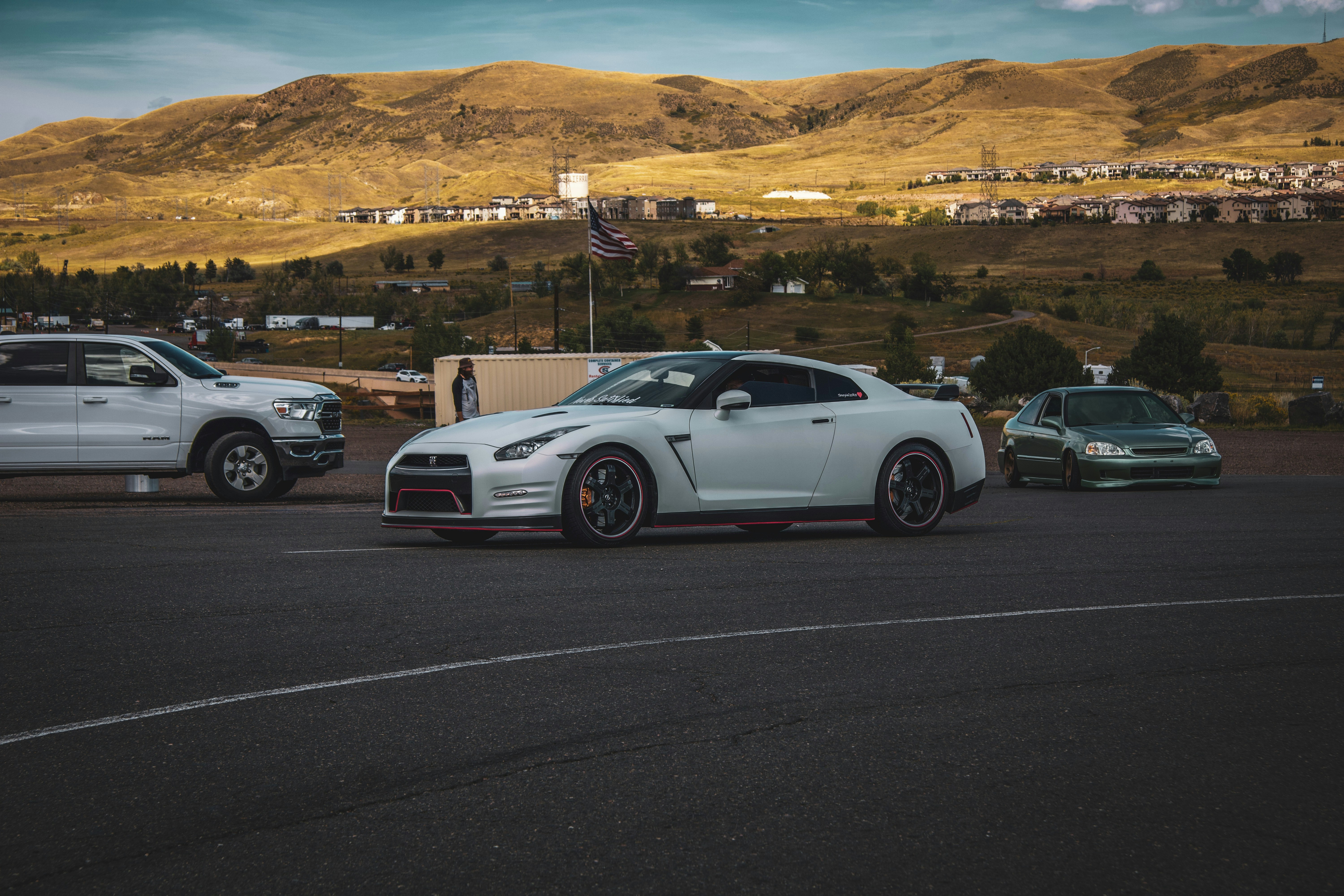 Three cars parked in a parking lot with mountains in the background
