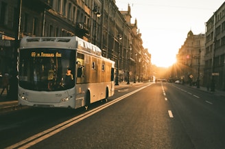 White luxury bus with tinted windows on a city street during sunset.