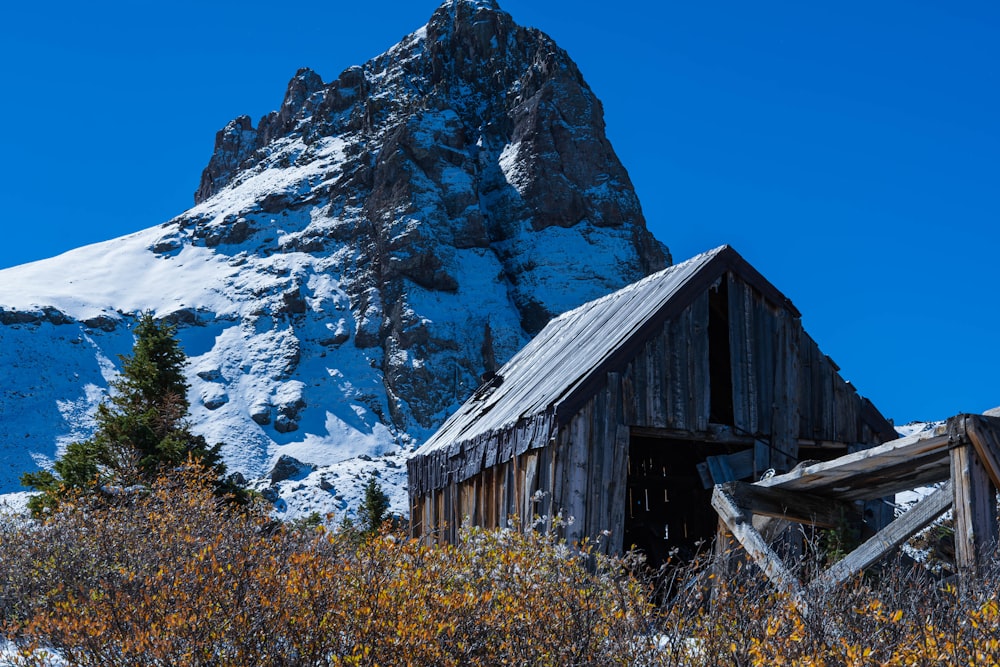 an old barn in the mountains with a mountain in the background