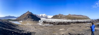 a man standing on top of a mountain next to a glacier