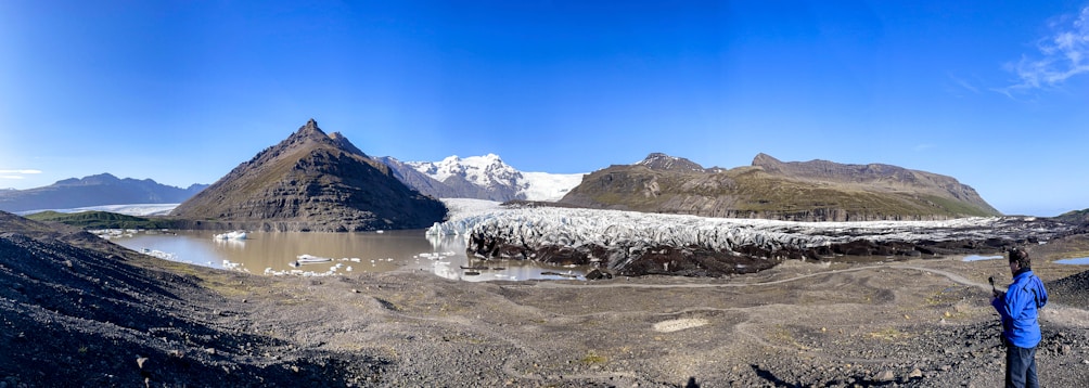 a man standing on top of a mountain next to a glacier