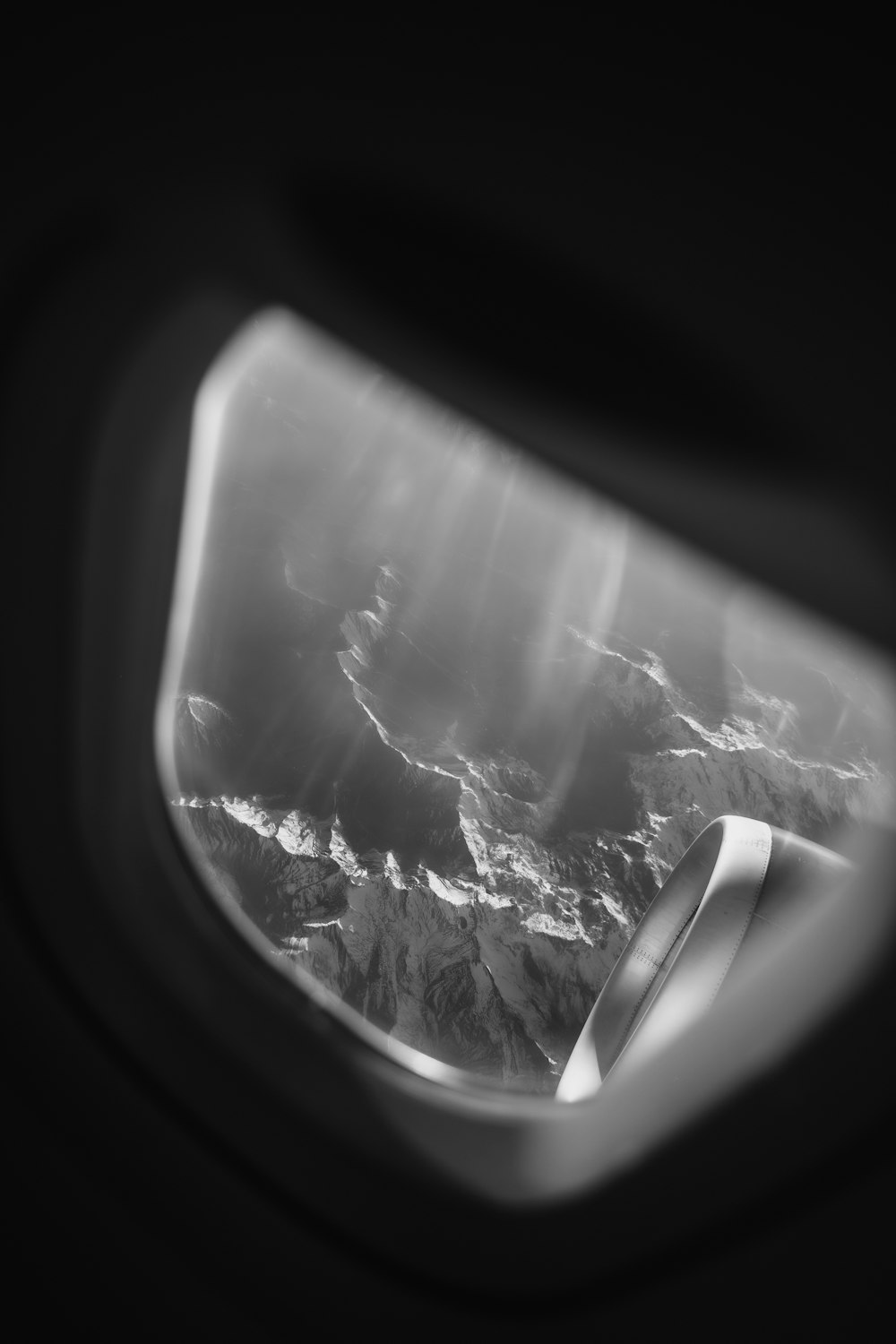 an airplane window with a view of a mountain range