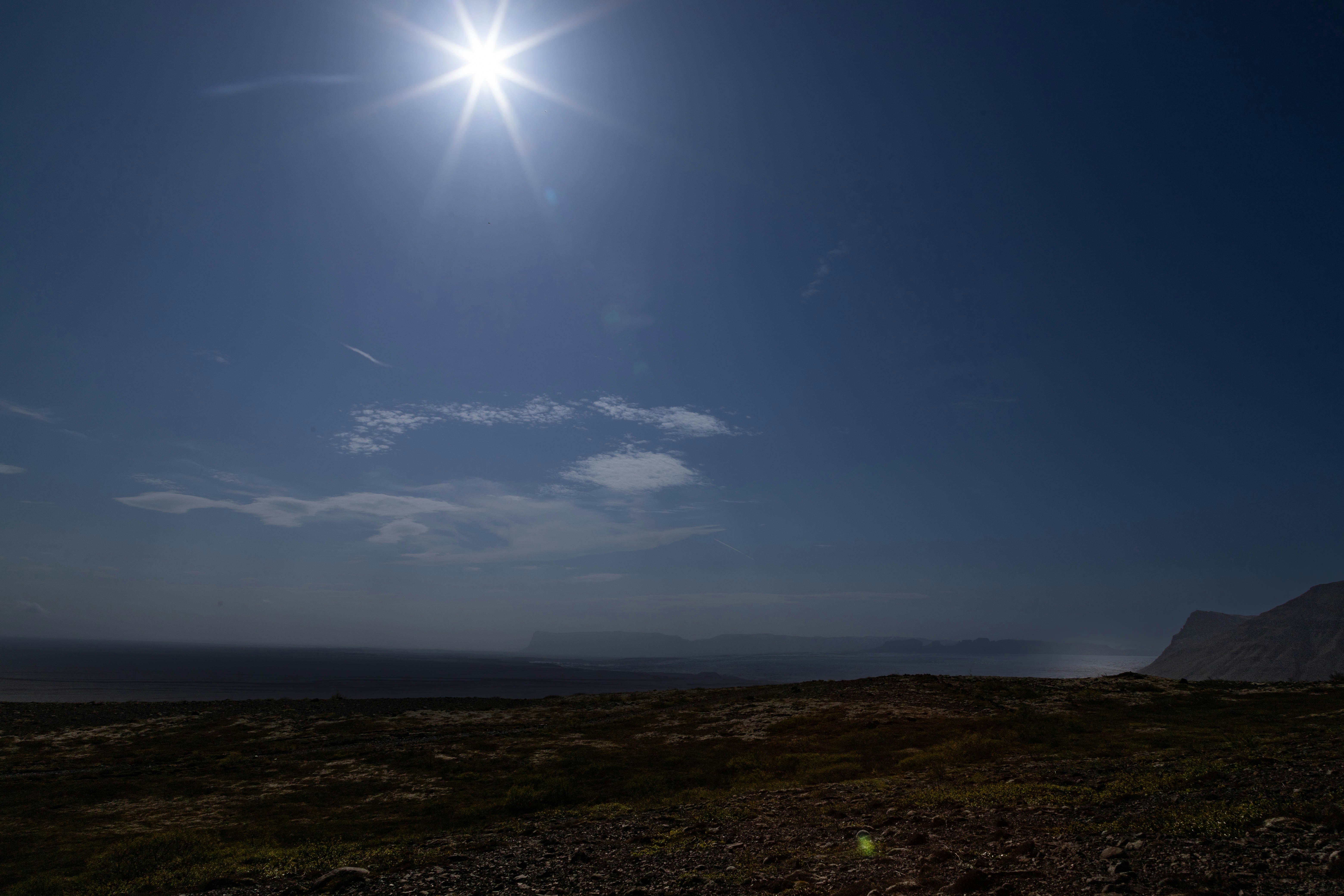 the sun shines brightly in the sky above a grassy field