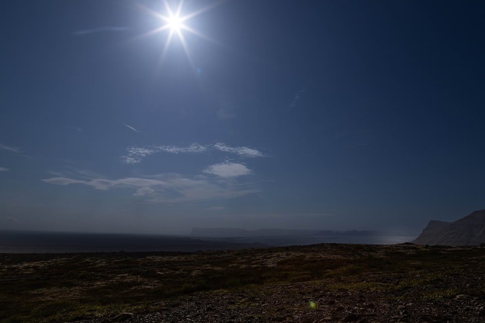 the sun shines brightly in the sky above a grassy field