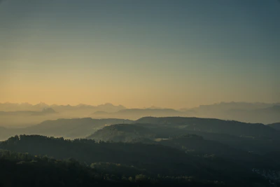 A serene landscape at dawn with soft pastel skies over rolling hills.