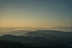 A serene landscape capturing the soft light of dawn over rolling hills.