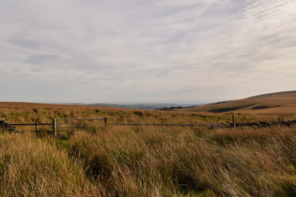 a wooden fence in a grassy field with mountains in the background