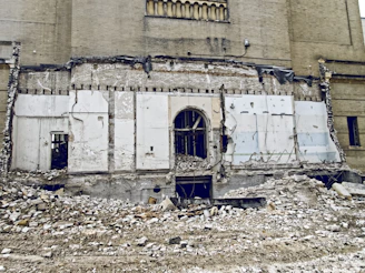 Demolition scene showing controlled breaking of a concrete wall with safety measures in place.