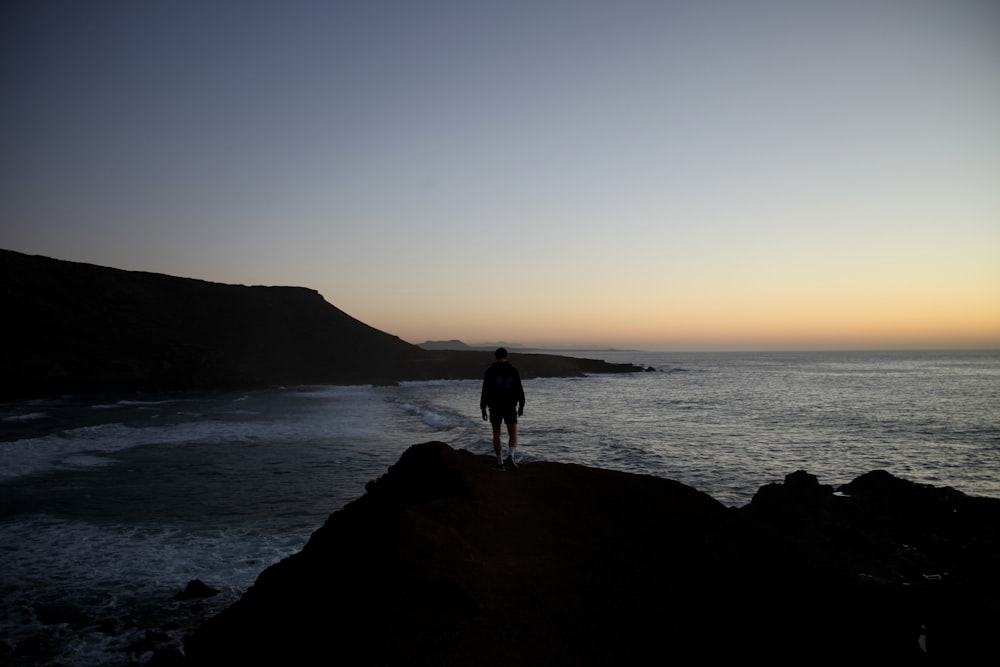 a person standing on a rock near the ocean