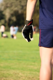 An active player adjusting a knee support before a ball game on a sunny field.