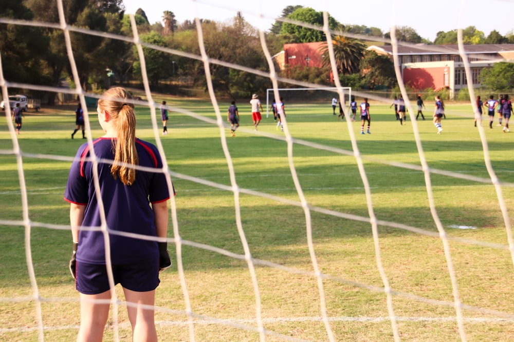 uma menina em pé na frente de um gol de futebol