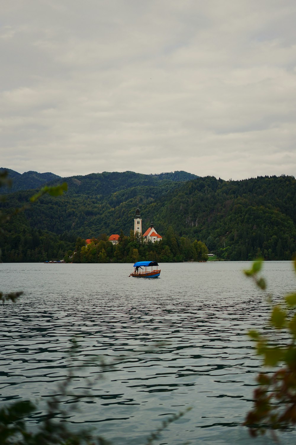 a boat floating on top of a lake next to a lush green hillside