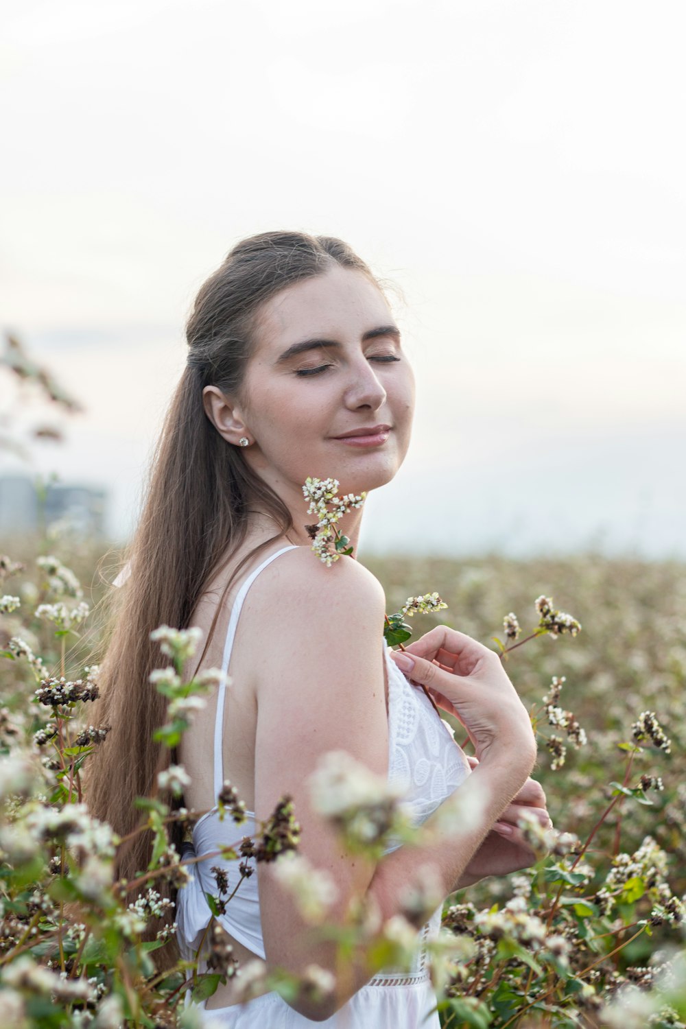 a woman standing in a field holding a flower