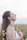 A close-up of a smiling woman enjoying a peaceful moment outdoors.