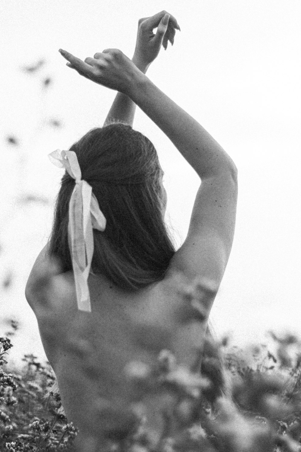 a woman in a field reaching up to a bird