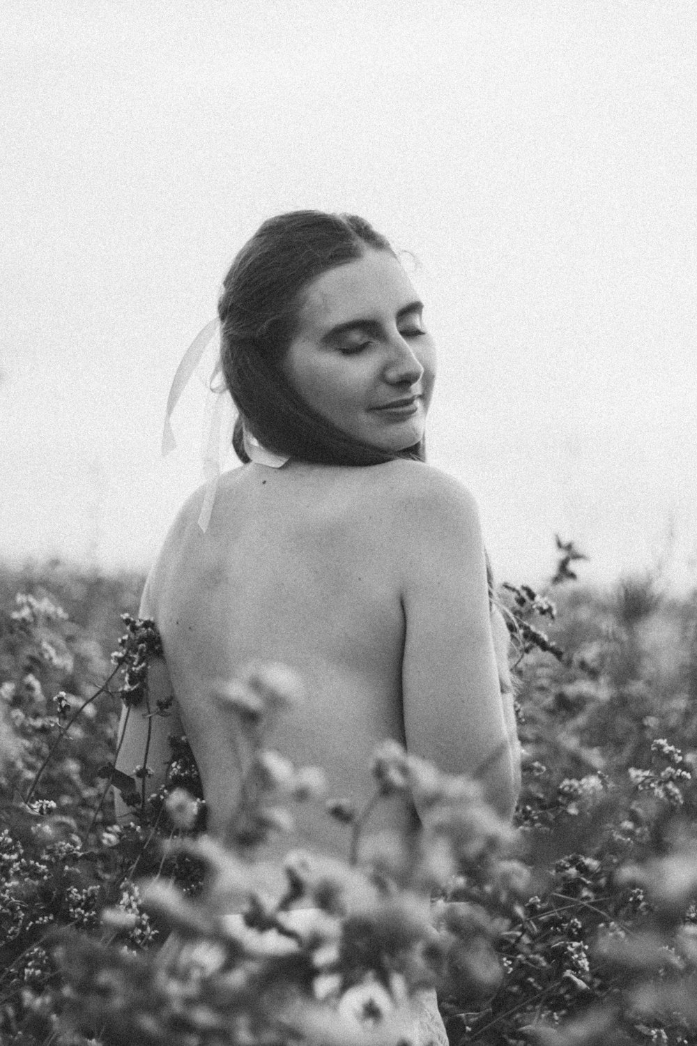 a naked woman standing in a field of flowers