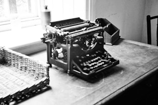 A cozy writing desk with a vintage typewriter and a cup of coffee beside a window.