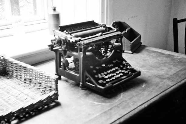 A writer's desk with scattered scripts, a vintage typewriter, and a warm cup of coffee by a window.